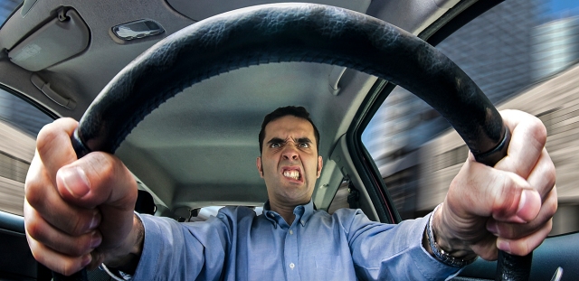 A furious man driving, as seen from behind the wheel. Shot using a very wide fisheye lens.